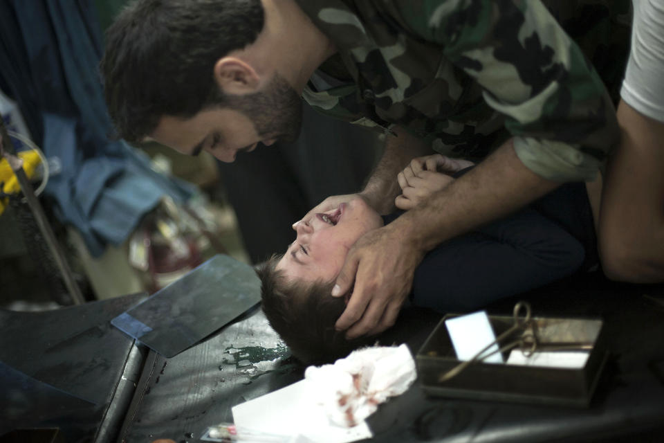 FILE - In this Thursday, Oct. 11, 2012 file photo, a Free Syrian Army fighter comforts a child wounded by Syrian Army artillery shelling, at Dar al-Shifa hospital in Aleppo, Syria. Syria’s uprising was not destined to be quick. Instead, the largely peaceful protest movement that spread across the nation slowly turned into an armed insurgency and eventually a full-blown civil war. More than 130,000 people have been killed, and more than 2 million more have fled the country. Nearly three years after the crisis began, Syria's government and opposition are set to meet in Geneva this week for the first direct talks aimed at ending the conflict. (AP Photo/ Manu Brabo, File)