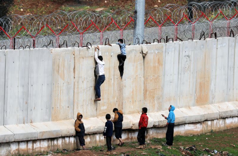 Internally displaced Syrian boys climb the wall in Atmah IDP camp, located near the border with Turkey