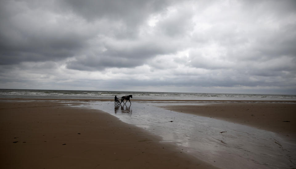 A man rides in a horse drawn sulky on Omaha Beach, during a partial lifting of coronavirus measures, in Saint-Laurent-sur-Mer, Normandy, France, Thursday June 4, 2020. (AP Photo/Virginia Mayo)