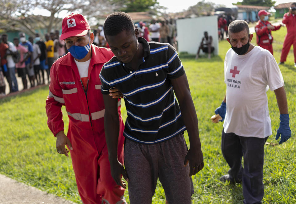 A sick Haitian immigrant is helped by a member of the Red Cross at a campground being used to house a large group of Haitian migrants in Sierra Morena in Cuba's Villa Clara province, Thursday, May 26, 2022. A vessel carrying more than 800 Haitians trying to reach the United States wound up instead on the coast of central Cuba, in what appeared to be the largest group seen yet in a swelling exodus from crisis-stricken Haiti. (AP Photo Ramon Espinosa)