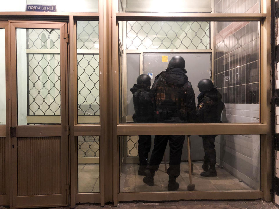 Police stand in front of a door of the apartment building where Oleg Navalny, brother of jailed opposition leader Alexei Navalny lives in Moscow, Russia, Wednesday, Jan. 27, 2021. Police are searching the Moscow apartment of jailed Russian opposition leader Alexei Navalny, another apartment where his wife is living and two offices of his anti-corruption organization. Navalny's aides reported the Wednesday raids on social media. (AP Photo/Mstyslav Chernov)