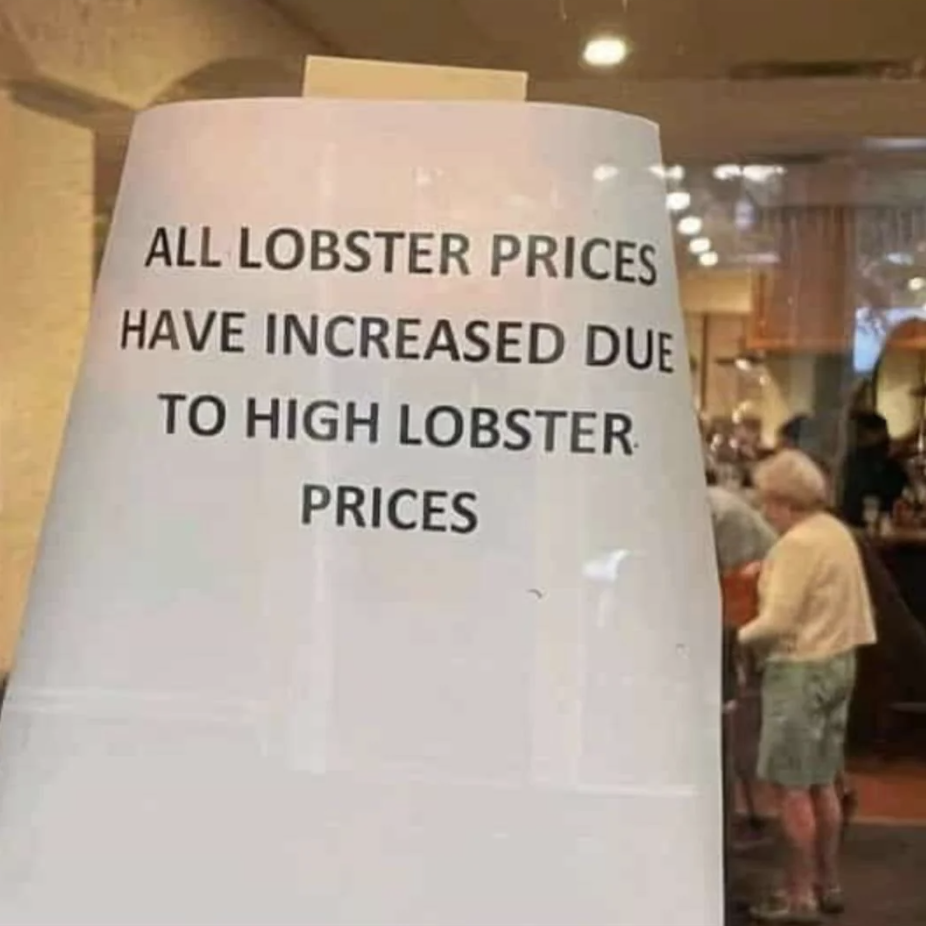 Sign reads "ALL LOBSTER PRICES HAVE INCREASED DUE TO HIGH LOBSTER PRICES," with a person in the background