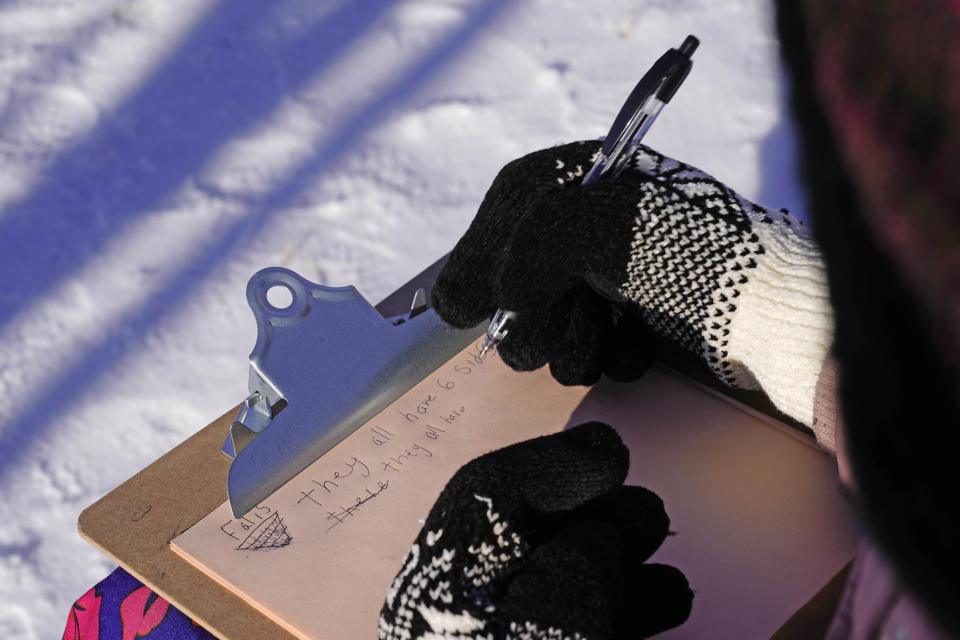 In this Monday, Dec. 8, 2020 photo, fourth grader Falis Asair makes notes while wearing gloves during an outdoor class at the Gerald Talbot School, in Portland, Maine. (AP Photo/Robert F. Bukaty)