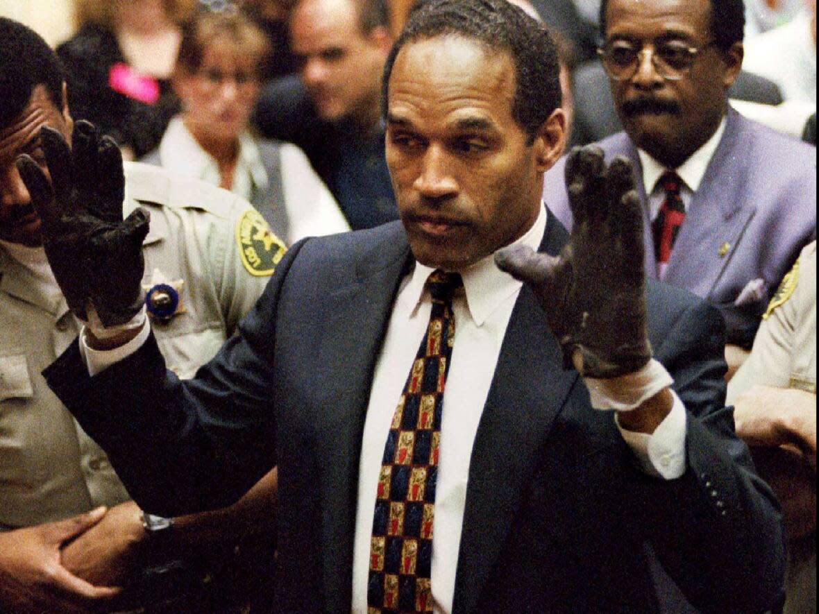 O.J. Simpson displays his hands to the jury at the request of prosecutor Christopher Darden in this file photograph from June 15, 1995 as his attorney Johnnie Cochran, Jr. looks on.    (Sam Mircovich/Reuters - image credit)