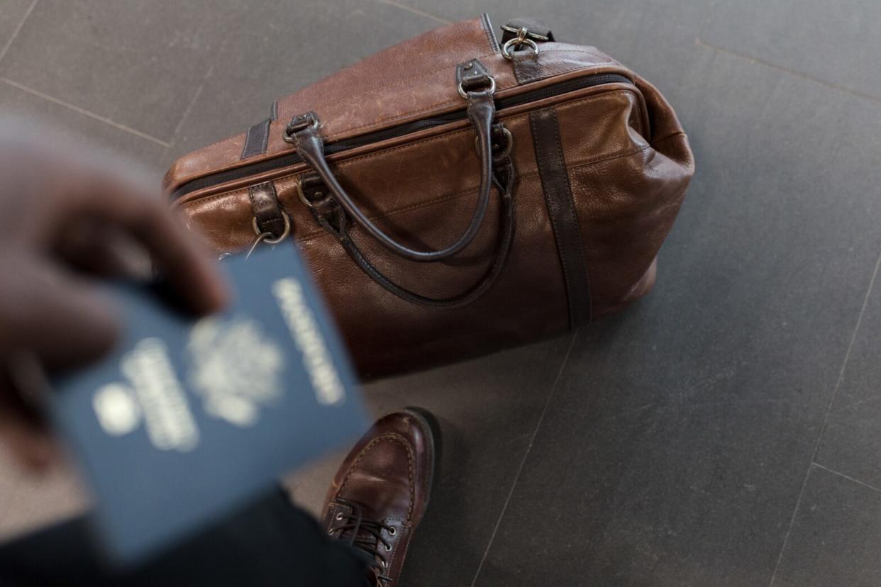 Is Global Entry worth it? Compare the program to other Trusted Traveler Programs like TSA PreCheck and CLEAR. Pictured: a person holding a passport with a travel bag on the ground.
