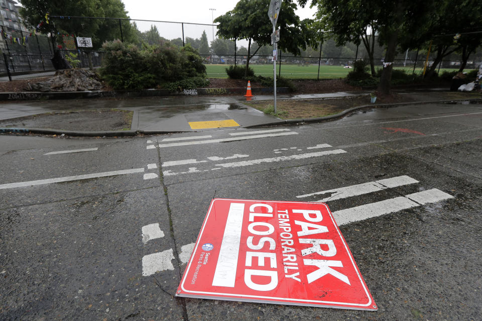 A sign that indicates Cal Anderson Park will be closed at noon lies in the street, Tuesday, June 30, 2020 at the CHOP (Capitol Hill Occupied Protest) zone in Seattle. Earlier in the day, workers removed concrete barricades at one intersection, but protesters quickly moved couches, trash cans and other materials to replace the barricades. The area has been occupied by protesters since Seattle Police pulled back from their East Precinct building following violent clashes with demonstrators earlier in the month. (AP Photo/Ted S. Warren)