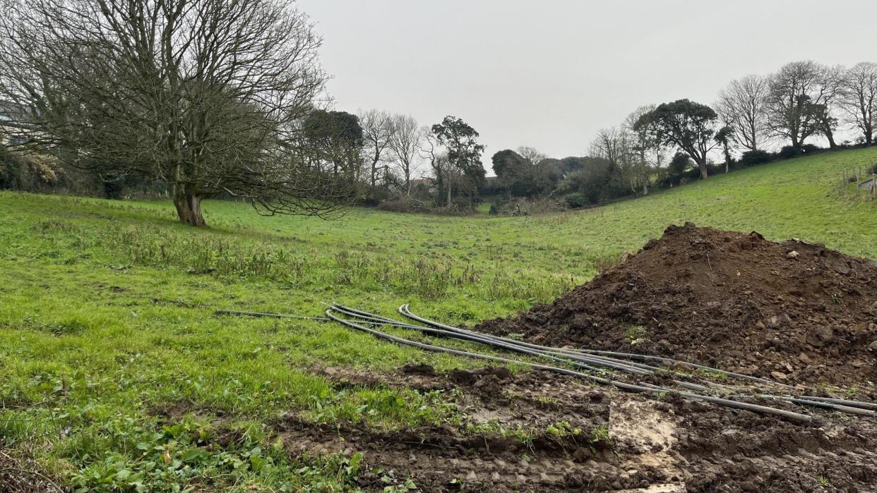 A muddy field with tyre marks and pipes