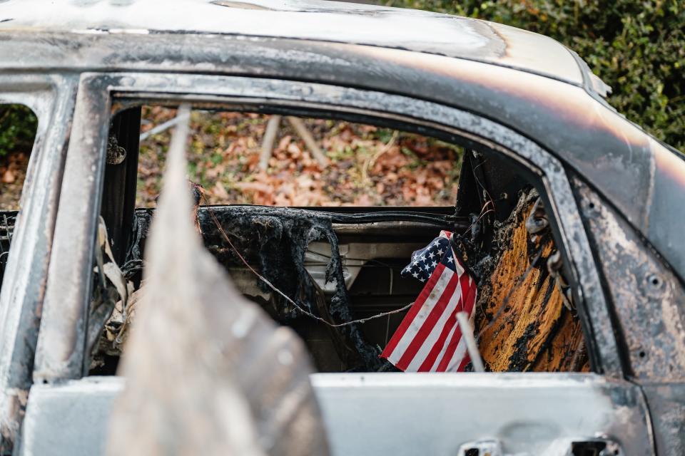 An American flag is left behind in the remains of a burned vehicle at Lincolns and Things on Tuesday in Sherrodsville. A Monday afternoon fire destroyed the structure, which also warehoused approximately 8,000 toys for the Tuscarawas County Toys for Tots.