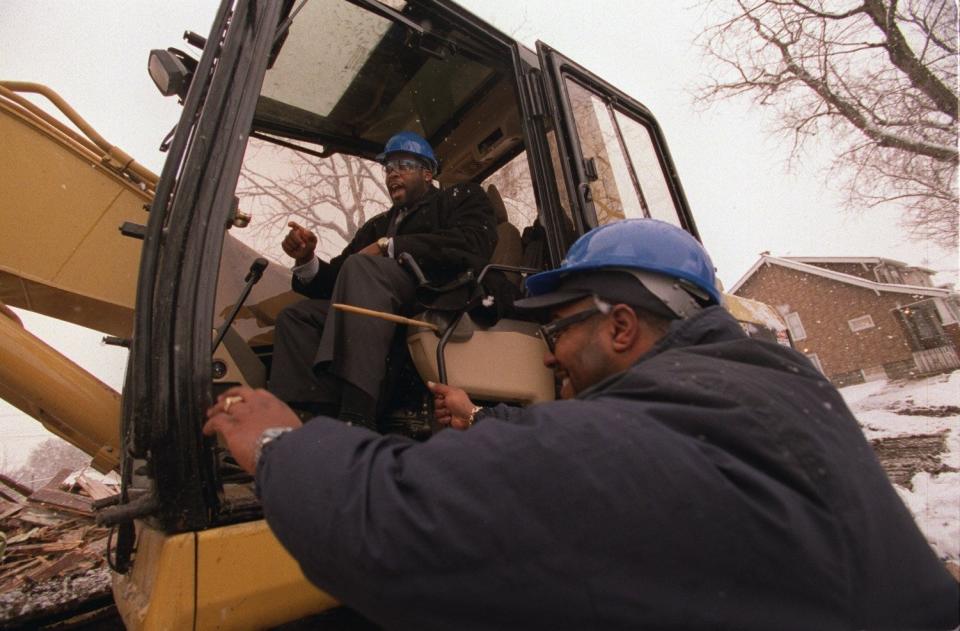 Detroit Mayor Kwame Kilpatrick grabs the controls of backhoe from Bobby Ferguson, of Ferguson Enterprises Inc., on  Wednesday, Jan. 30, 2002 during the demolition of three different abandoned houses on Mountclair Street near Joy Middle School.