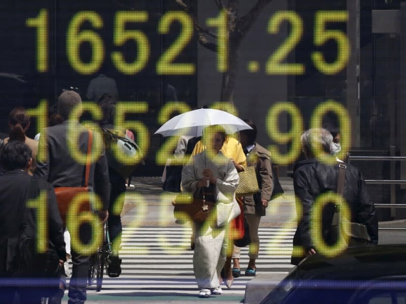 FILE PHOTO - A woman clad in a kimono is reflected in an electronic board displaying Japan's Nikkei share average outside a brokerage in Tokyo, Japan, April 18, 2016. REUTERS/Toru Hanai