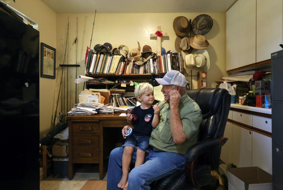 A boy sits on a man's lap in a home office