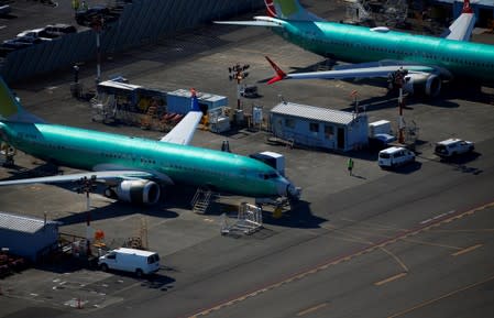 FILE PHOTO: A worker walks past unpainted Boeing 737 MAX aircraft parked at Renton Municipal Airport in Renton