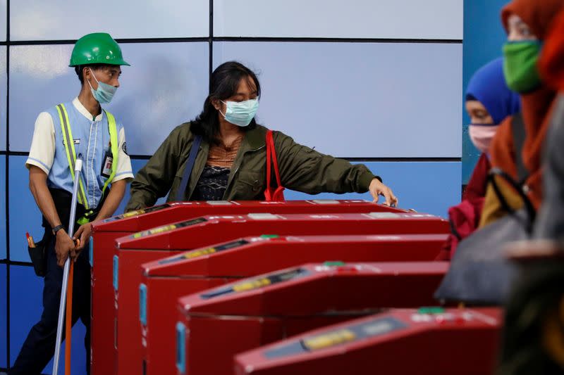 Passengers wearing protective masks pass the entrance gate of Juanda train station following confirmed cases of the novel coronavirus disease of COVID-19 in Jakarta