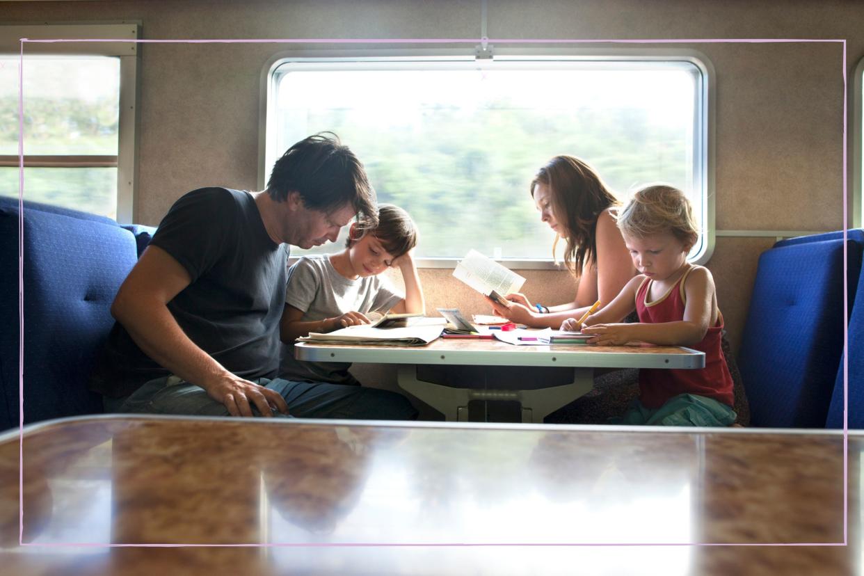 Family including two children entertained while sitting at a table on a train. 