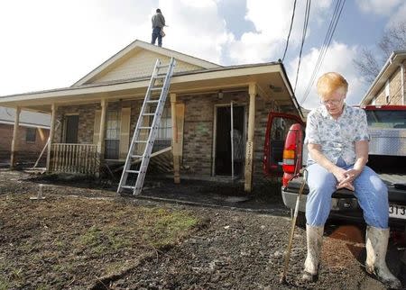 Elizabeth Weaver sits on the back of a truck outside her flood damaged home while an insurance adjustor checks the damage to her roof in St. Bernard Parish east of New Orleans, Louisiana November 9, 2005. REUTERS/Lucas Jackson