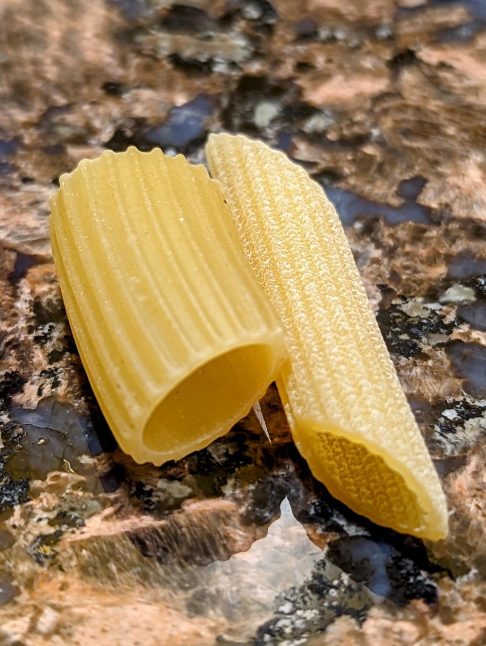 Two pieces of uncooked pasta on a textured surface