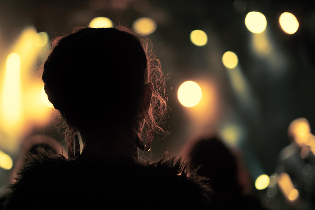 Back lit photograph of a woman watching a performance at a music event in Colmar, France.