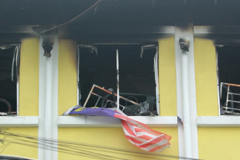 A Malaysian national flag flutters outside burnt windows of the Darul Quran Ittifaqiyah religious school in Kuala Lumpur on September 14, 2017