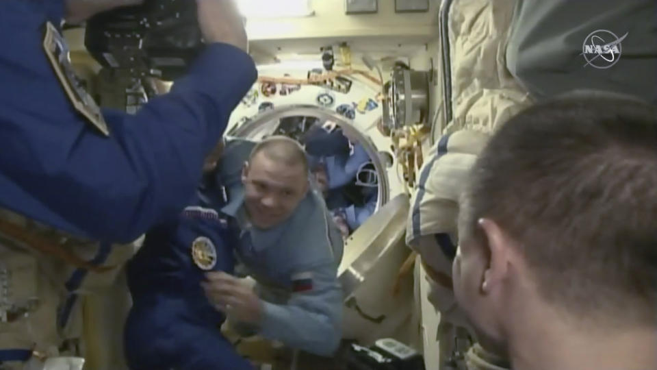 In this image from video made available by NASA, International Space Station crew members welcome cosmonauts Ivan Vagner, center, Anatoly Ivanishin and astronaut Chris Cassidy, obscured, as they exit the Soyuz capsule docked to the station on Thursday, April 9, 2020. (NASA via AP)