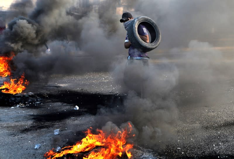 An Iraqi demonstrator burns tires to block a road, during ongoing anti-government protests, in Kerbala