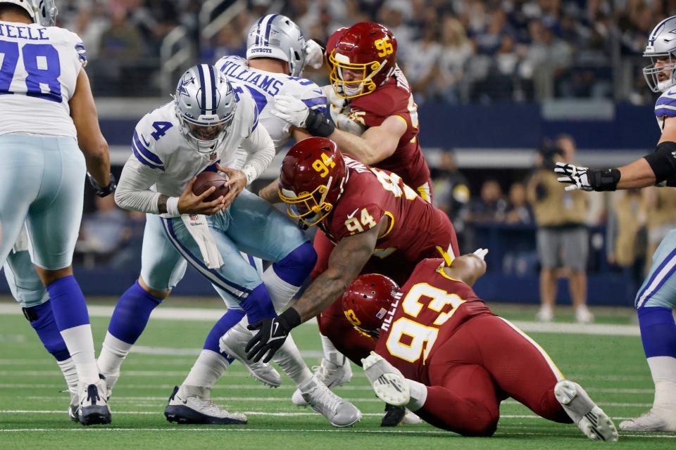 Dallas Cowboys' Dak Prescott (4) is tackled by Washington Football Team's Daron Payne (94) and Jonathan Allen (93) in the first half of an NFL football game in Arlington, Texas, Sunday, Dec. 26, 2021. (AP Photo/Michael Ainsworth)