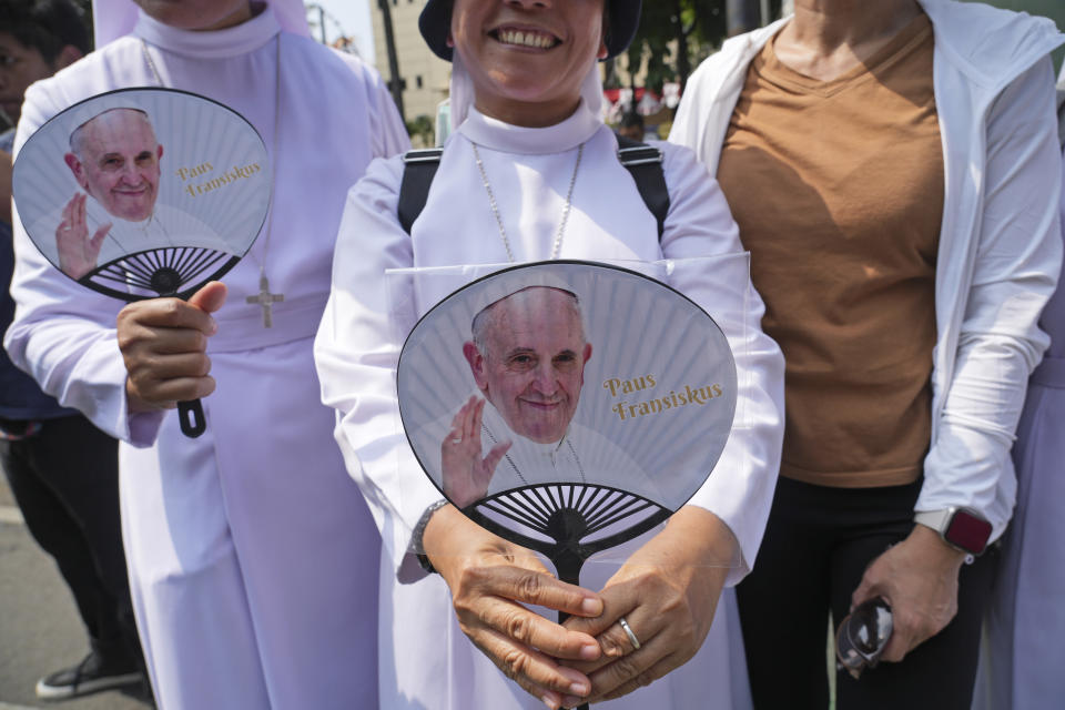 Fieles equipadas con abanicos con la cara del papa Francisco esperan en el exterior de la sede de la Conferencia Episcopal de Indonesia para saludar al papa, antes de una reunión, en Yakarta, Indonesia, el 5 de septiembre de 2024. (AP Foto/Tatan Syuflana)