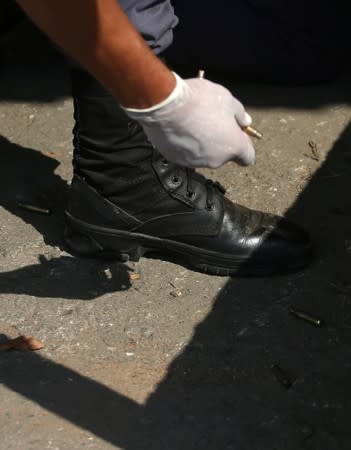 A police officer collects bullets near a site where an armed gang holds people hostage after they robbed a securities company at the Viracopos airport freight terminal, in Campinas