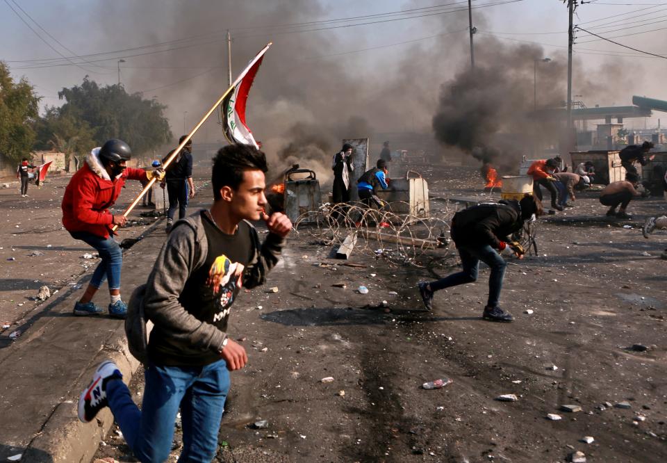 Anti-government protesters take cover while security forces use tear gas during clashes in central Baghdad, Iraq, Monday, Jan. 20, 2020. Iraqi security forces also used live rounds, wounding over a dozen protesters, medical and security officials said, in continuing violence as anti-government demonstrators make a push to revive their movement in Baghdad and the southern provinces. (AP Photo/Khalid Mohammed)