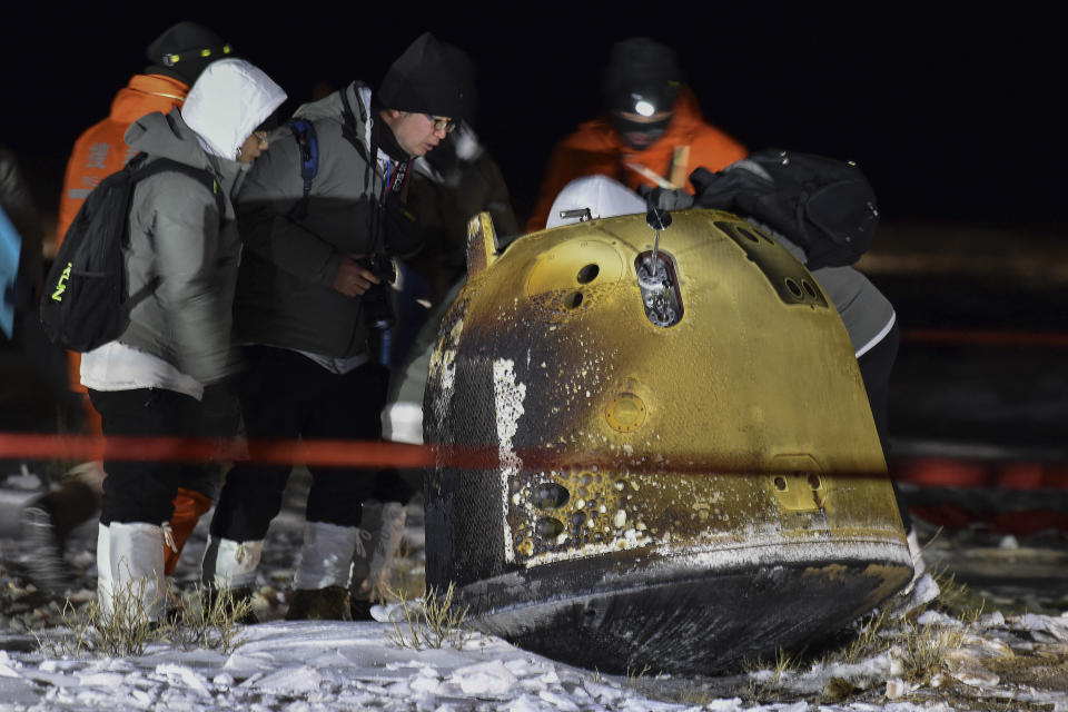 In this photo released by Xinhua News Agency, recovery crew members check on the capsule of the Chang'e 5 probe after its successful landed in Siziwang district, north China's Inner Mongolia Autonomous Region on Thursday, Dec. 17, 2020. A Chinese lunar capsule returned to Earth on Thursday with the first fresh samples of rock and debris from the moon in more than 40 years. (Ren Junchuan/Xinhua via AP)