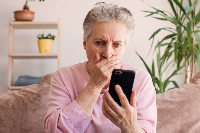 A woman looking shocked at something she's seeing on her phone