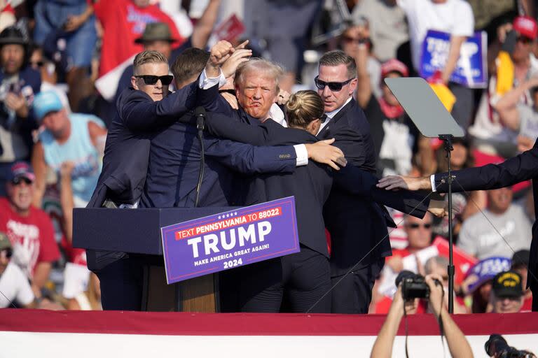 El candidato presidencial republicano, el ex presidente Donald Trump, es rodeado por agentes del Servicio Secreto de Estados Unidos en un acto de campaña en Butler, Pensilvania, el sábado 13 de julio de 2024. (AP Photo/Gene J. Puskar)