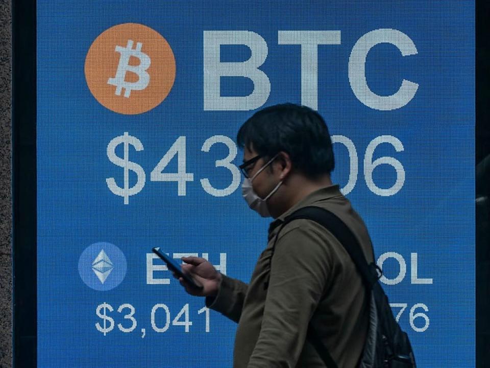 A pedestrian walks past a digital screen displaying the prices of cryptocurrencies bitcoin on 15 February, 2022, in Hong Kong (Getty Images)