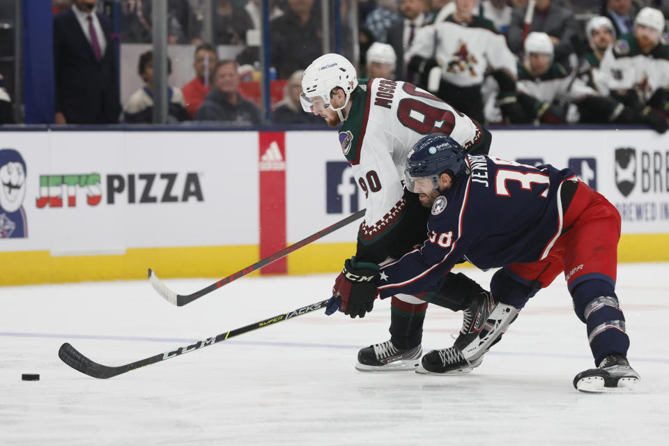Arizona Coyotes' J.J. Moser, left, and Columbus Blue Jackets' Boone Jenner chase a loose puck during the second period of an NHL hockey game Tuesday, Oct. 25, 2022, in Columbus, Ohio. (AP Photo/Jay LaPrete)