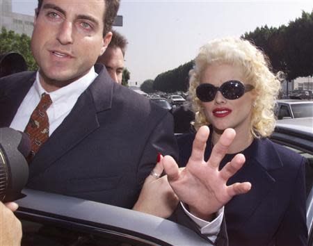 Model and former Playboy magazine Playmate Anna Nicole Smith is escorted by an unidentified attorney from her car as she arrives for opening arguments in her bankruptcy case at the Roybal Federal Building in Los Angeles, California in this October 27, 1999 file photo. REUTERS/Fred Prouser/Files