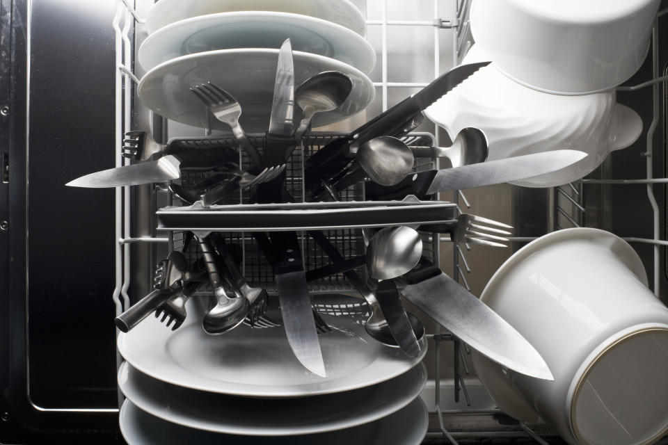 A dishwasher with plates, cups, and utensils after a cleaning cycle