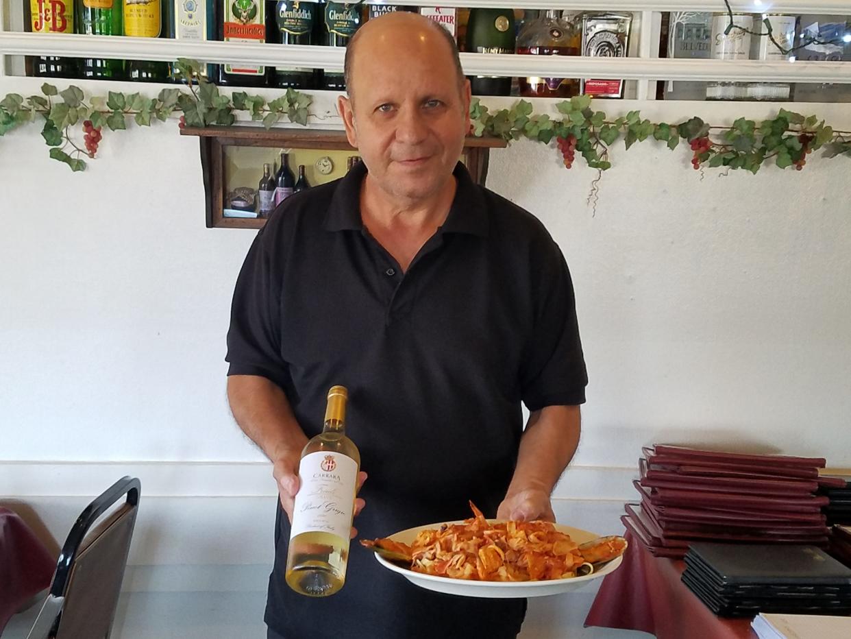 Juliano is able to pair the perfect wine with his pasta dishes. He holds a bottle of Carrera Pinot Grigio and a place of Fettuccini Pescadori.