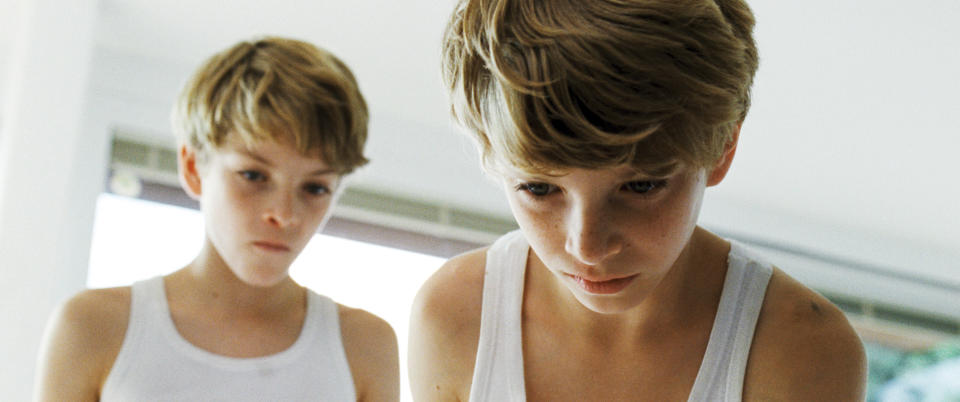 Twin boys look down at something offscreen