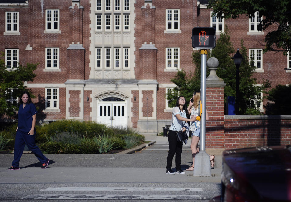 FLE- In this Sept. 18, 2015 file photo, a University of Connecticut student waits for the traffic light to change outside of a dormitory building on the University of Connecticut campus in Storrs, Conn. The University of Connecticut said on Saturday, July 18, 2020, that all residential students returning to the Storrs or Stamford campuses must be tested for COVID-19 two weeks before the first day of classes. (AP Photo/Jessica Hill)