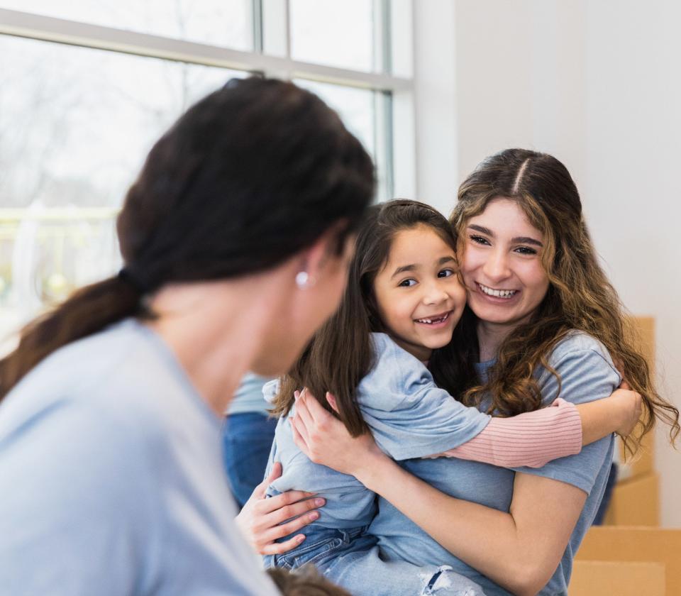 A young aunt holds her niece as they both smile