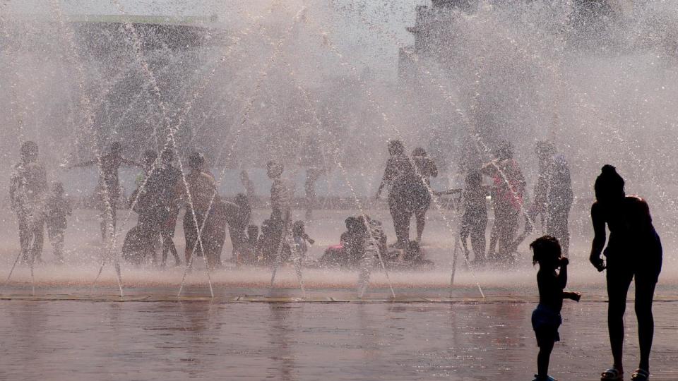 PHOTO: A woman attends to a young child at the edge of the water fountain on the Christian Science Plaza while others escape the heat in the water, in Boston, June 19, 2024. (Cj Gunther/EPA via Shutterstock)