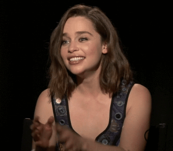 Woman smiling and clapping, wearing a sleeveless top with circular patterns