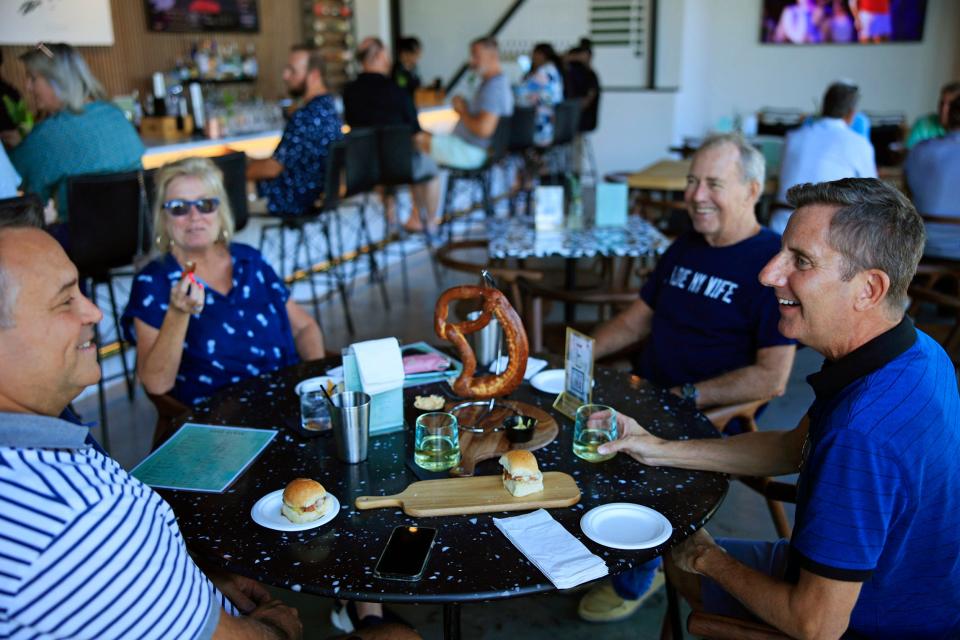 Bill Miles and Greg Moore (left to right n the foreground) and Kelli Williams and husband Richard enjoy a meal and some laughs Thursday at the newly opened Fore Score Golf Tavern on San Marco Square in Jacksonville. The sports-theme restaurant includes four golf simulators and other activities.