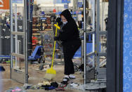 A woman cleans up debris at a Walmart, Wednesday, Oct. 28, 2020, that was damaged in protests in Philadelphia. Demonstrators protested the death of Walter Wallace Jr., who was fatally shot by police Monday after authorities say he ignored orders to drop a knife. Some businesses were cleaning up damage after video showed people streaming into stores and stealing goods on the opposite side of the city from where Wallace was shot. (AP Photo/Michael Perez)