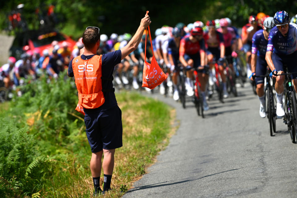 A soigneur carrying a musette of SiS nutrition for an Ineos rider