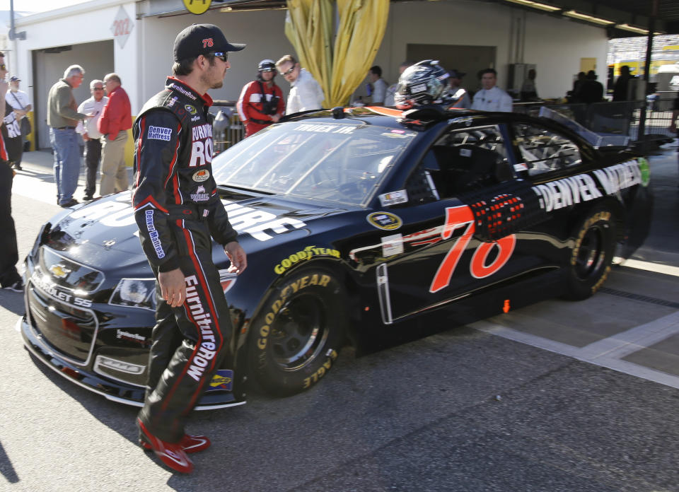 Martin Truex Jr. walks around his car after qualifying in the number two position for the Daytona 500 NASCAR Sprint Cup Series auto race at Daytona International Speedway in Daytona Beach, Fla., Sunday, Feb. 16, 2014. (AP Photo/John Raoux)