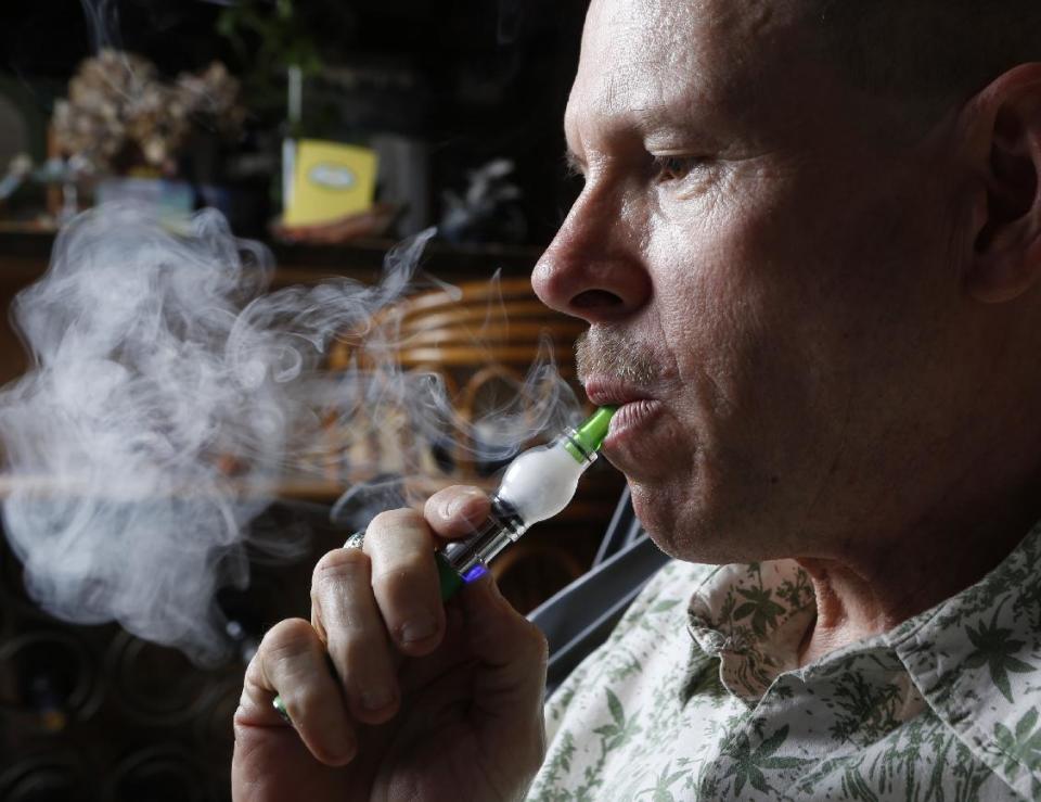 In this April 30, 2014 photo, Bill Britt, who suffers from epileptic seizures and leg pain from a childhood case of polio, vaporizes medical marijuana at his home in Long Beach, Calif. Britt lives mostly on Social Security income and gets his supply for free from a friend whom he helps water and grow the plants. Insurers are reluctant to cover medical marijuana because of conflicting laws and lack of approval from the U.S. Food and Drug Administration. (AP Photo/Damian Dovarganes)