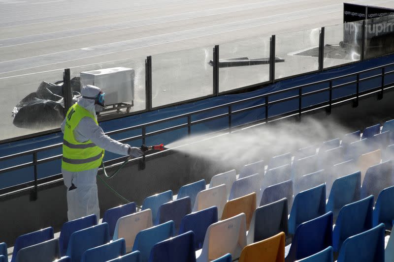 A cleaner wearing a protective suit sanitises seats at the San Paolo stadium ahead of the second leg of the Coppa Italia semi-final between Napoli and Inter Milan, which has since been postponed