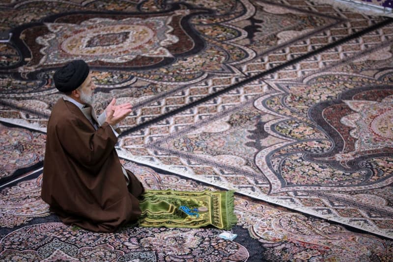 President of Iran Ebrahim Raisi prays after a meeting with a group of benefactors and officials of charitable institutions. -/Iranian Presidency/dpa