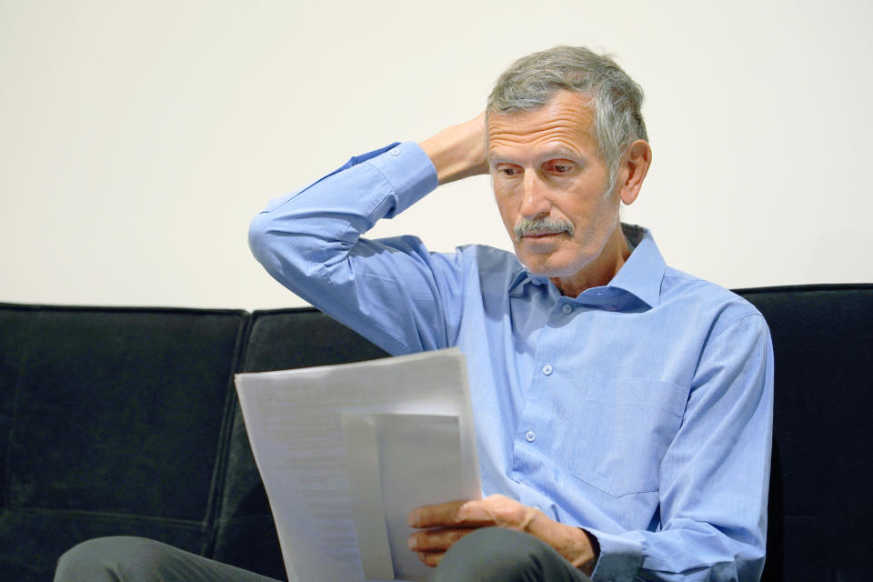 Senior man holding his head while reviewing document