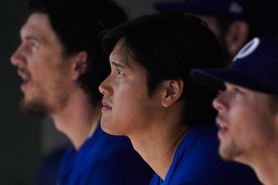 Los Angeles Dodgers designated hitter Shohei Ohtani sits in the dugout with teammates during a spring training baseball game against the Arizona Diamondbacks, Sunday, March 10, 2024, in Phoenix. (AP Photo/Lindsey Wasson)